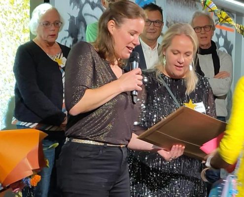 Winnaar verkiezing Uitblinker in besturen bekijkt samen met de uitreiker naar de prijs.